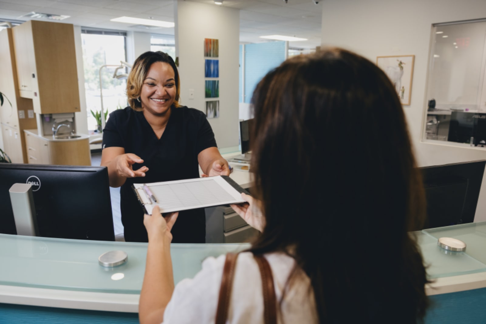 Female patient smiling during consultation with female dentist at reception desk