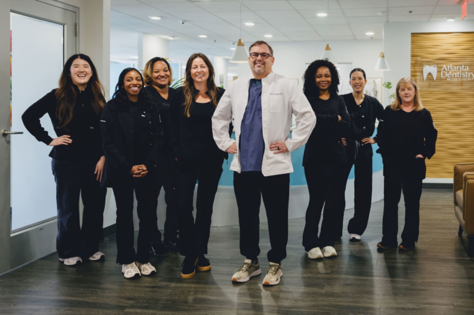 Atlanta Dentistry by Design team members posing together in a modern dental office hallway.