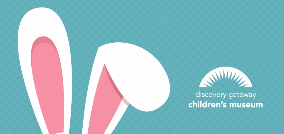 Illustration of two large white and pink bunny ears on a blue patterned background, with the Discovery Gateway Children’s Museum logo featuring a semicircle with rays and the museum name in white text on the right side.