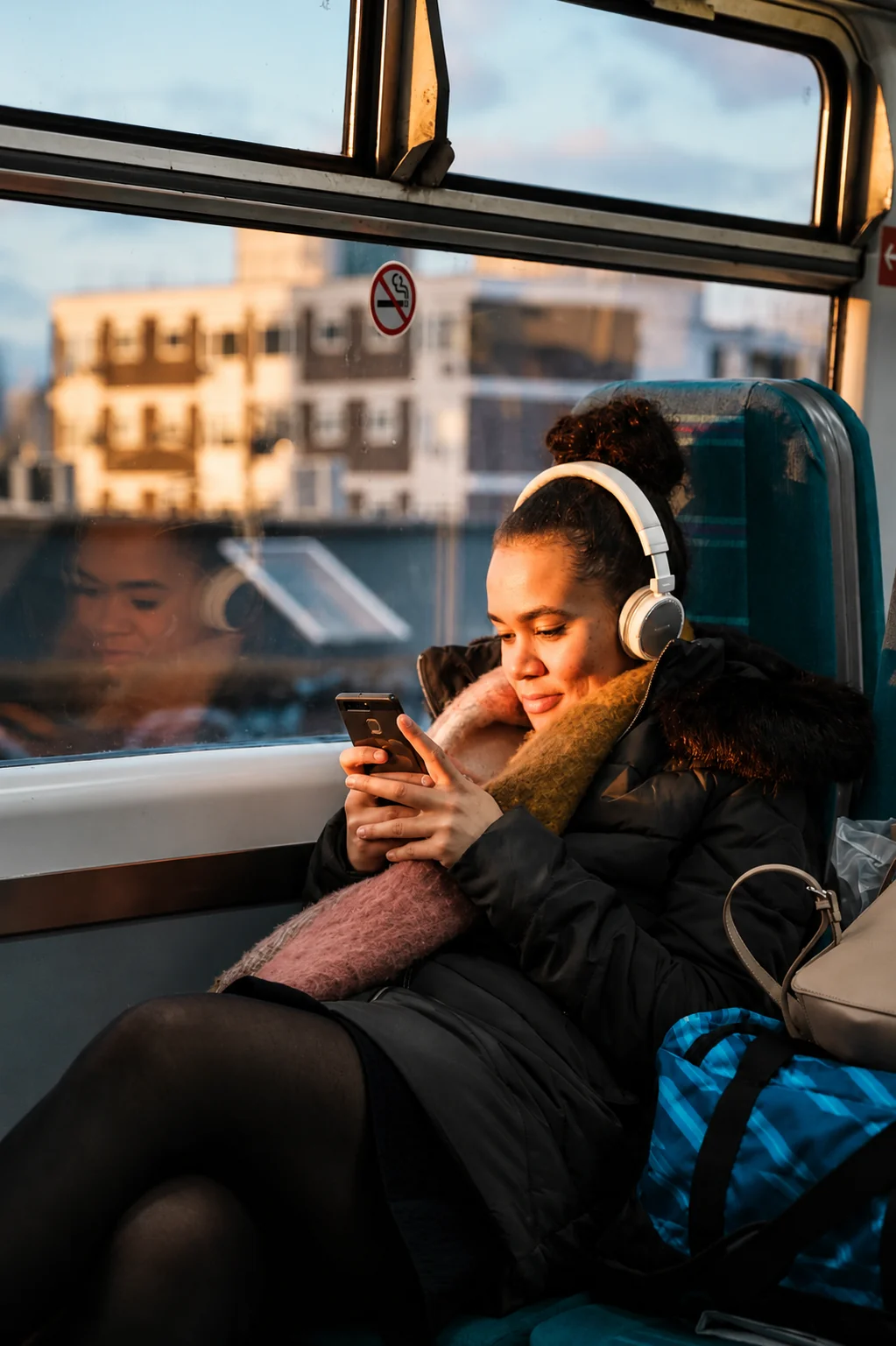 Woman wearing headphones using her phone on a train