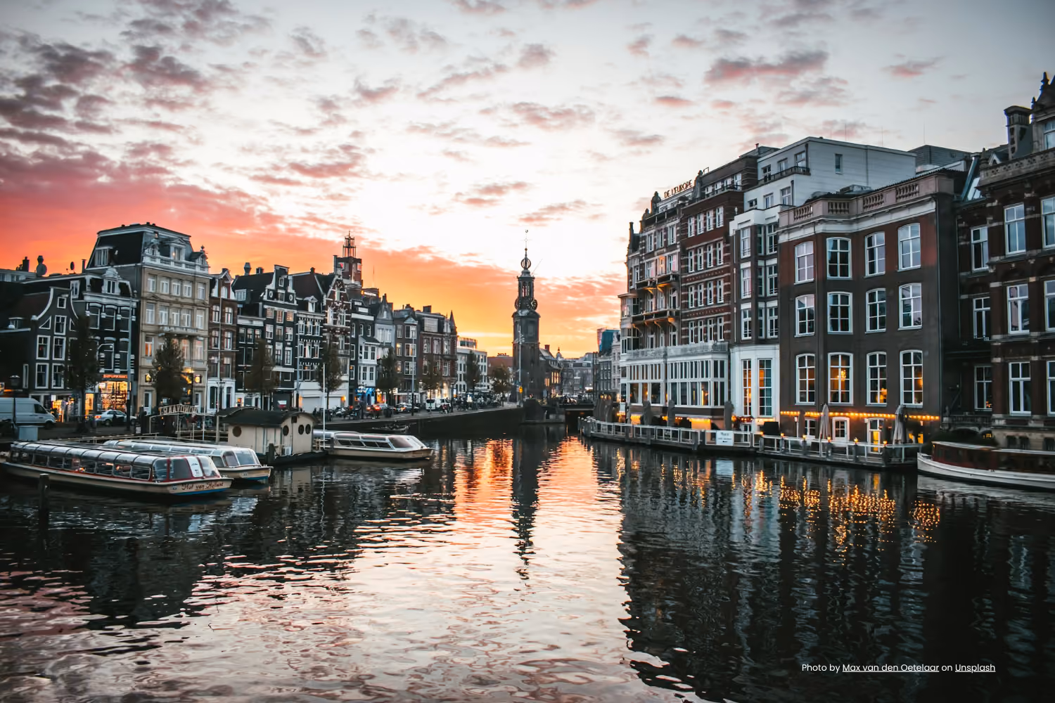 Canal houses and boats along an Amsterdam canal at sunset