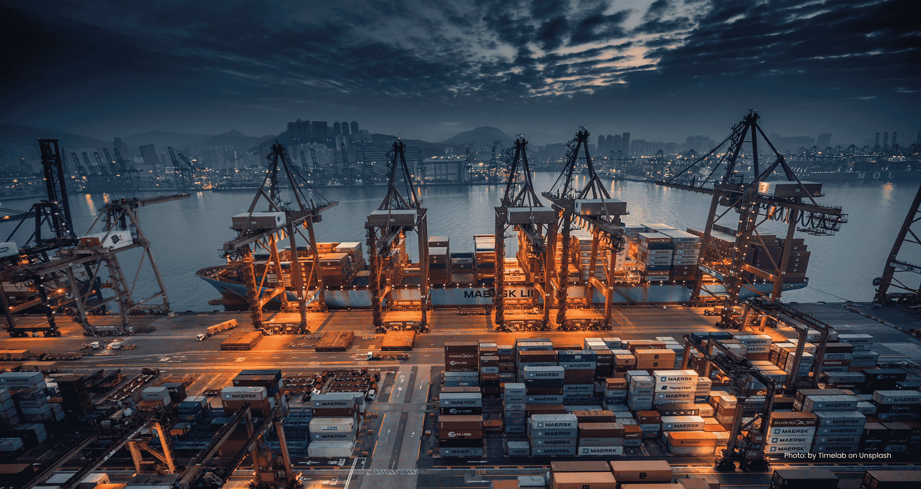 Container ship being loaded by gantry cranes at a port at dusk