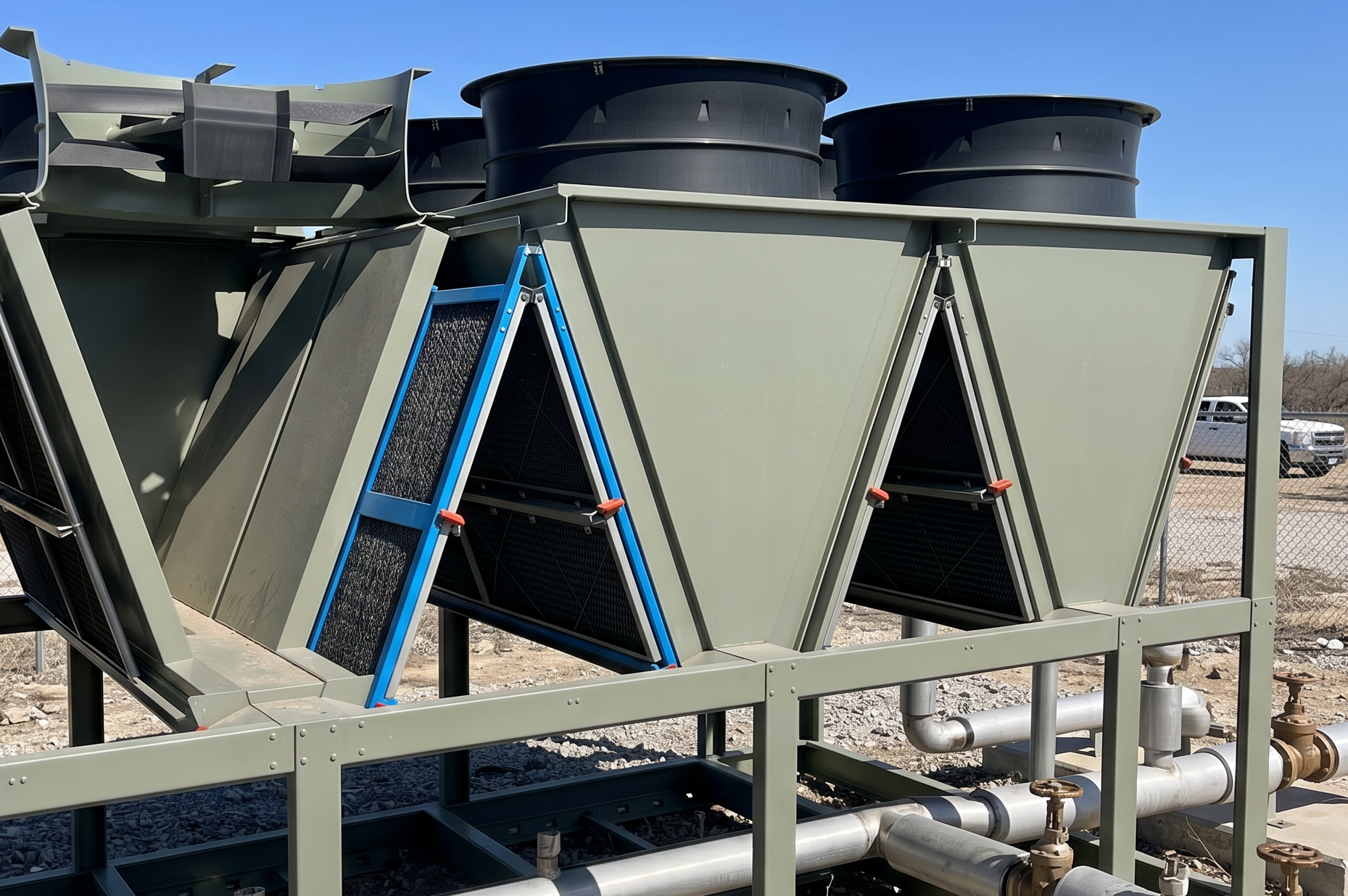 Large industrial HVAC cooling units with fans, filters, and metal framework outdoors on a sunny day.