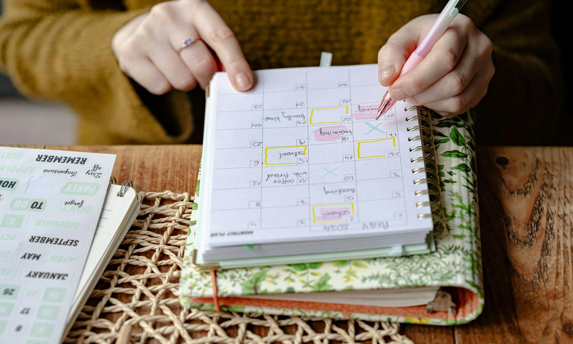 Hands marking a weekly planner with a pink pen.