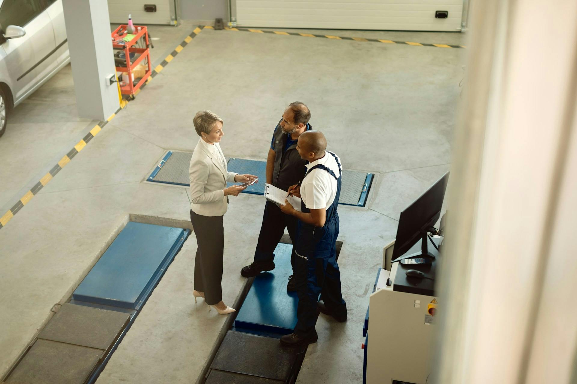 Overhead view of three people reviewing paperwork on a factory floor.