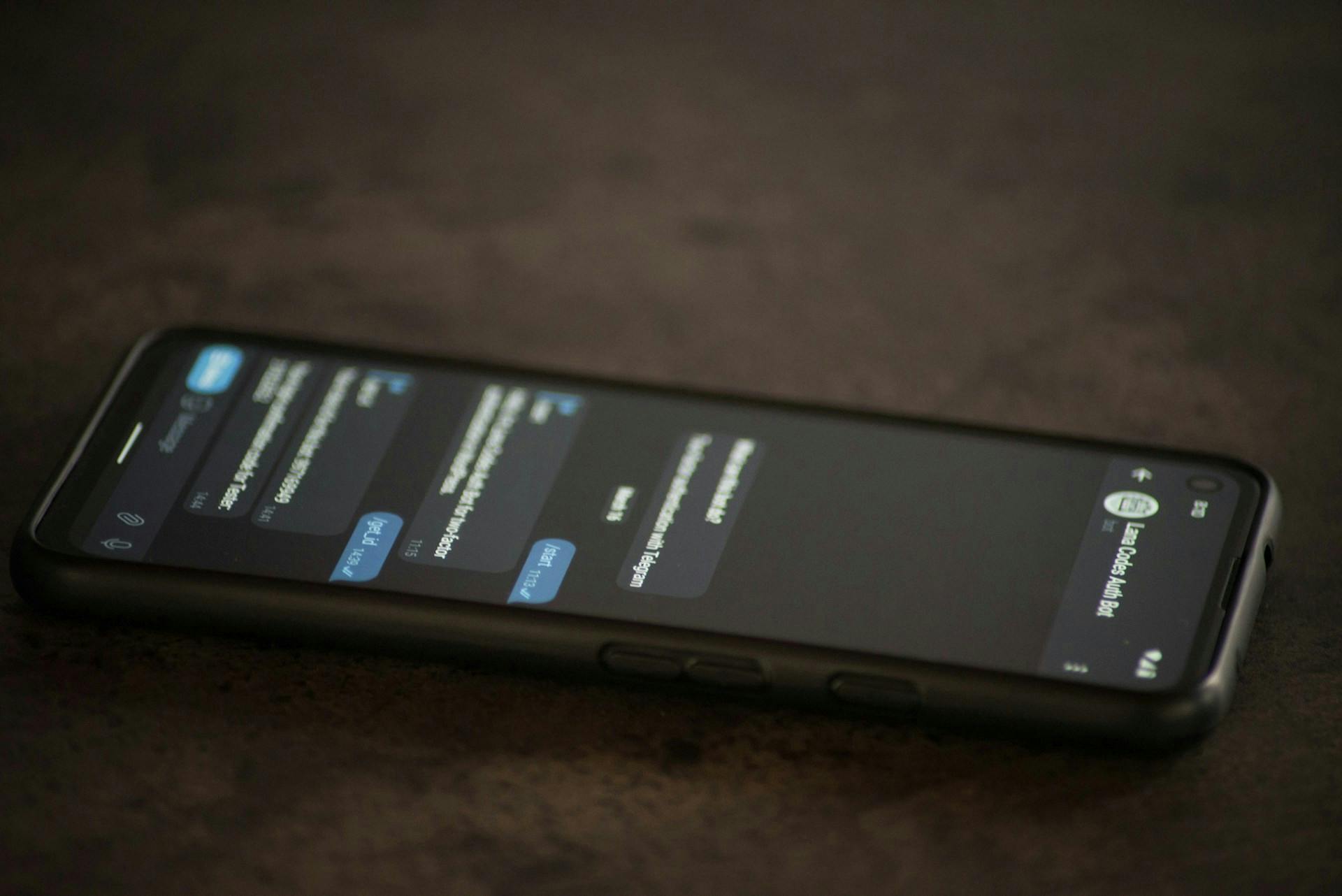 Smartphone displaying a text-message conversation on a dark tabletop.