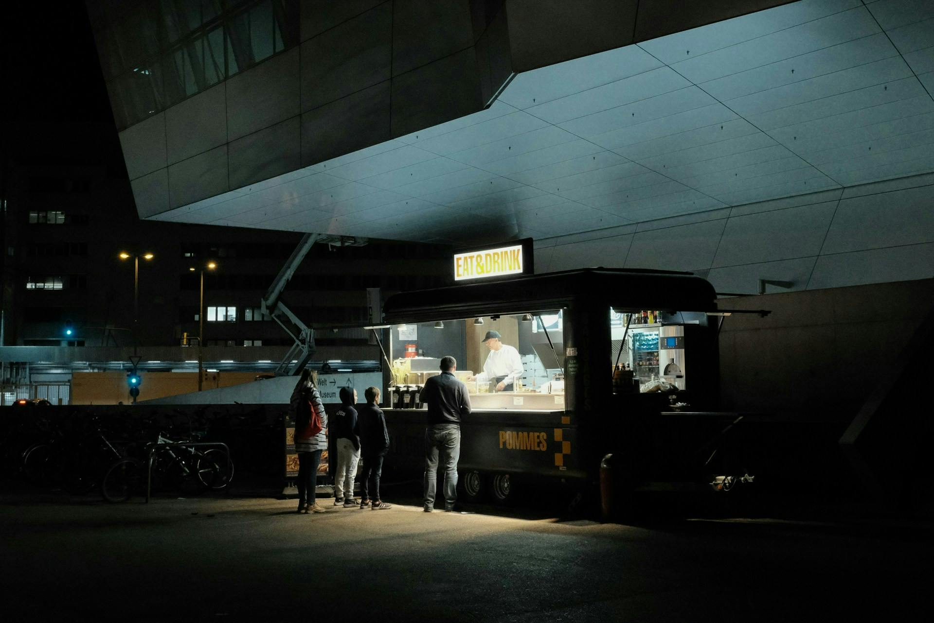Customers gathered at an illuminated food truck at night.