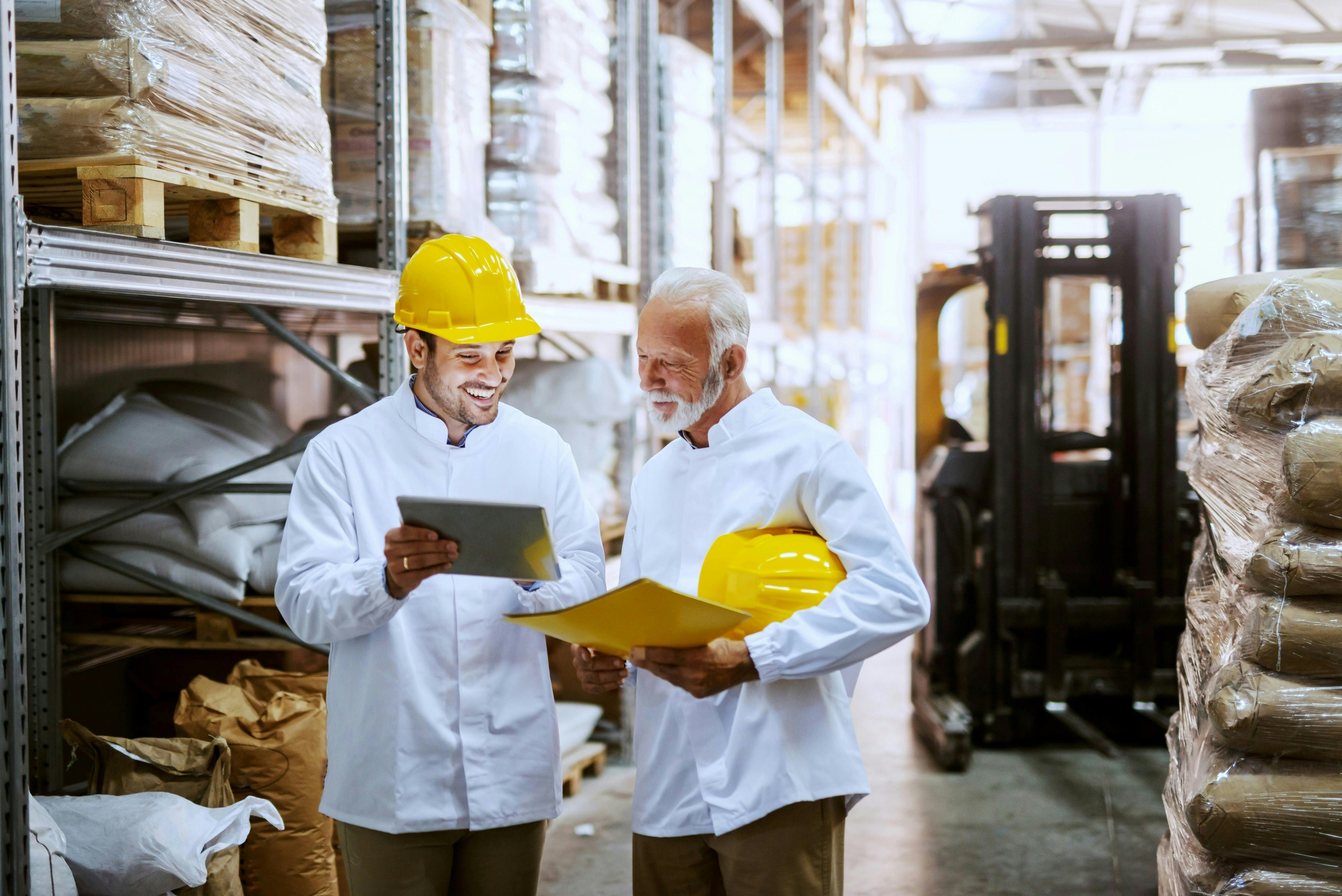 Two warehouse workers smiling at a tablet together.