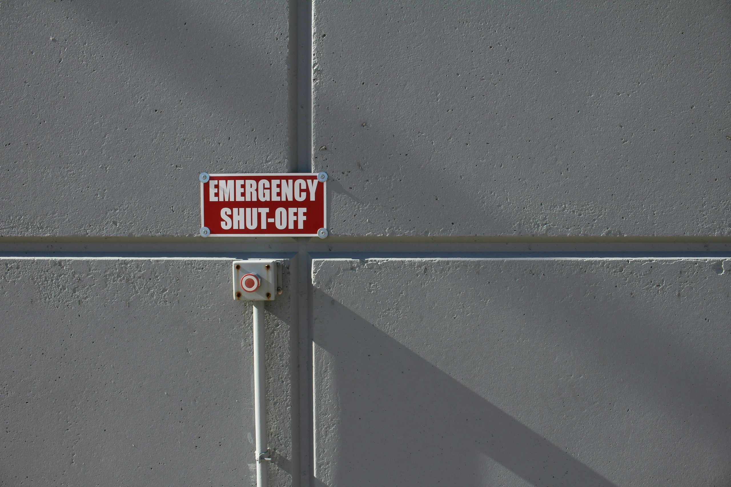 Red emergency shut-off sign on concrete wall