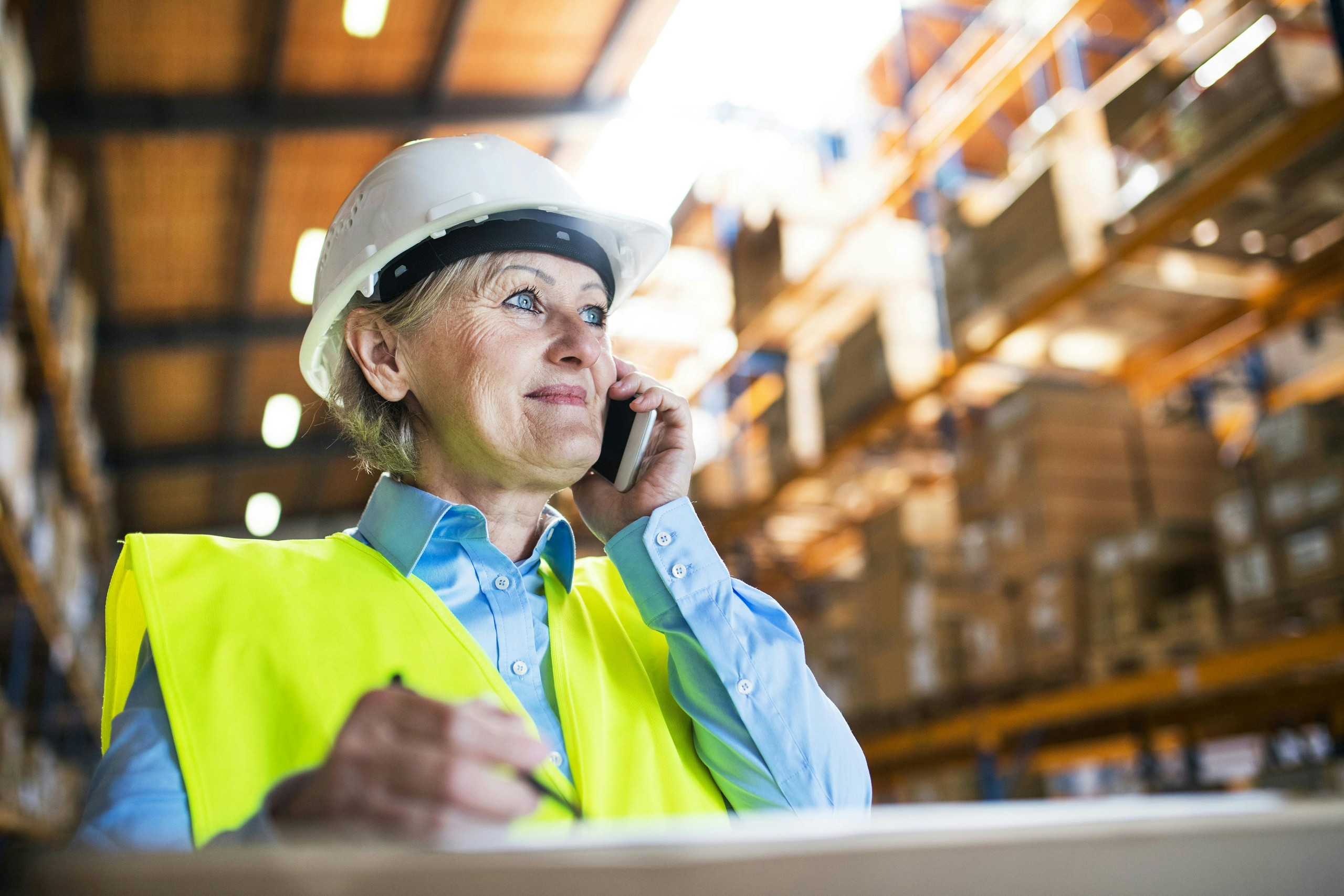 Warehouse worker in hard hat talking on phone