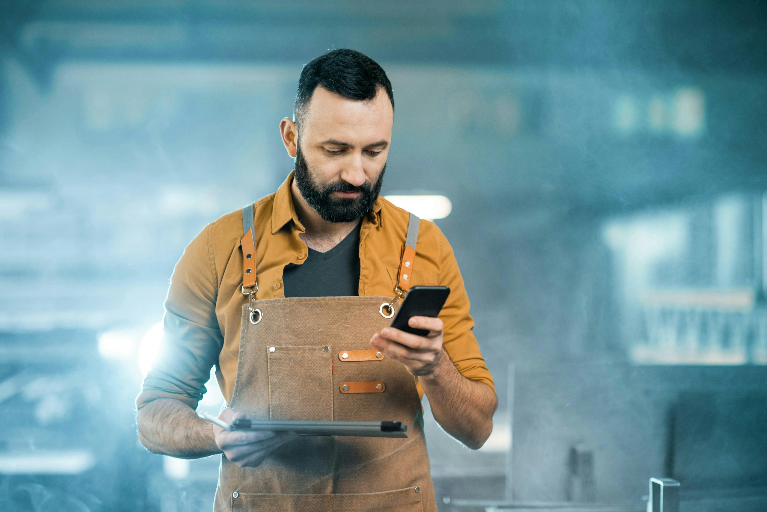 Worker in a work apron looking at a smartphone.
