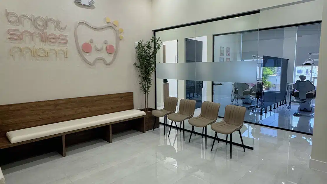 Bright Smiles Miami Modern dental office lobby with wooden bench, four chairs, wall decor, and glass door to treatment rooms.