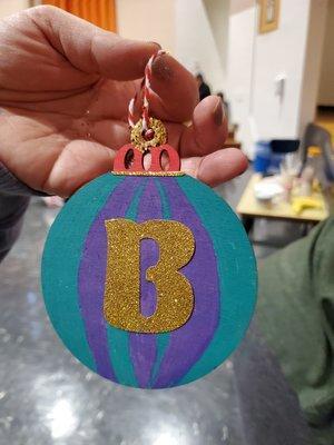 Student holding handmade ornament decorated with glitter letter B
