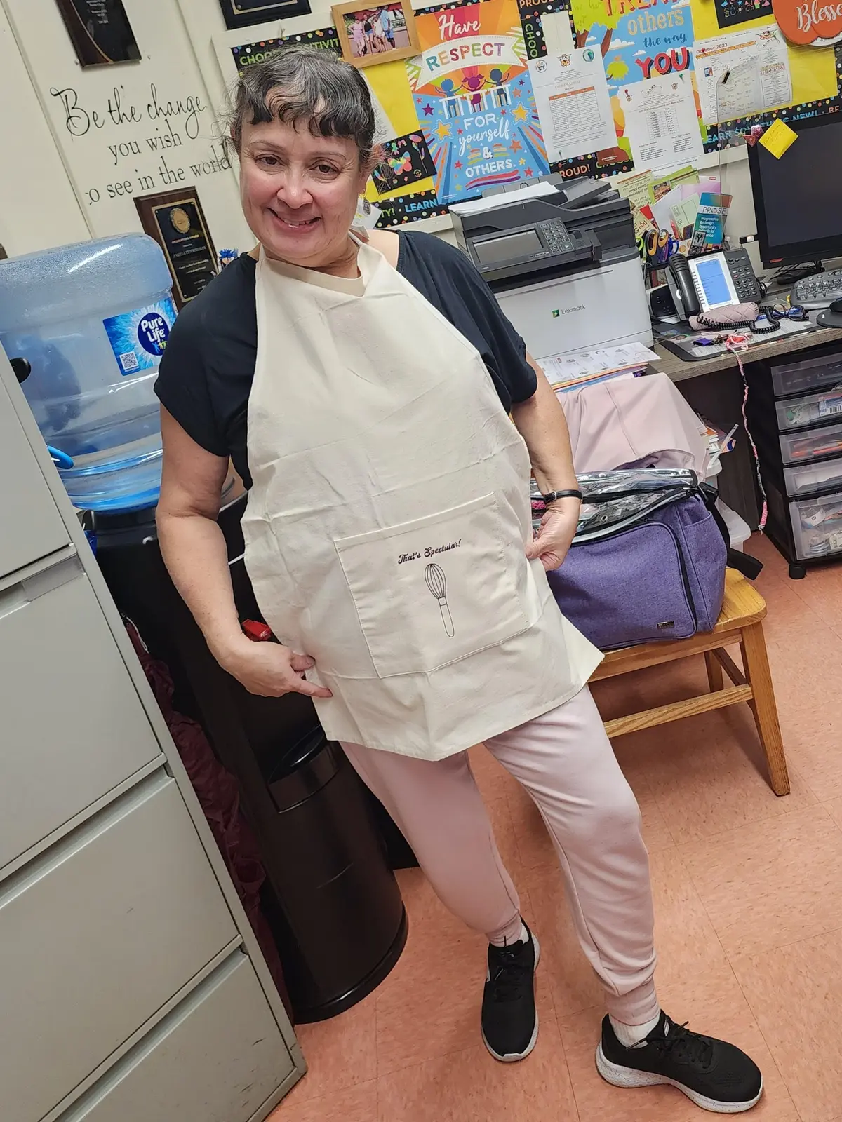 Teacher smiling and wearing a decorative cooking apron in classroom