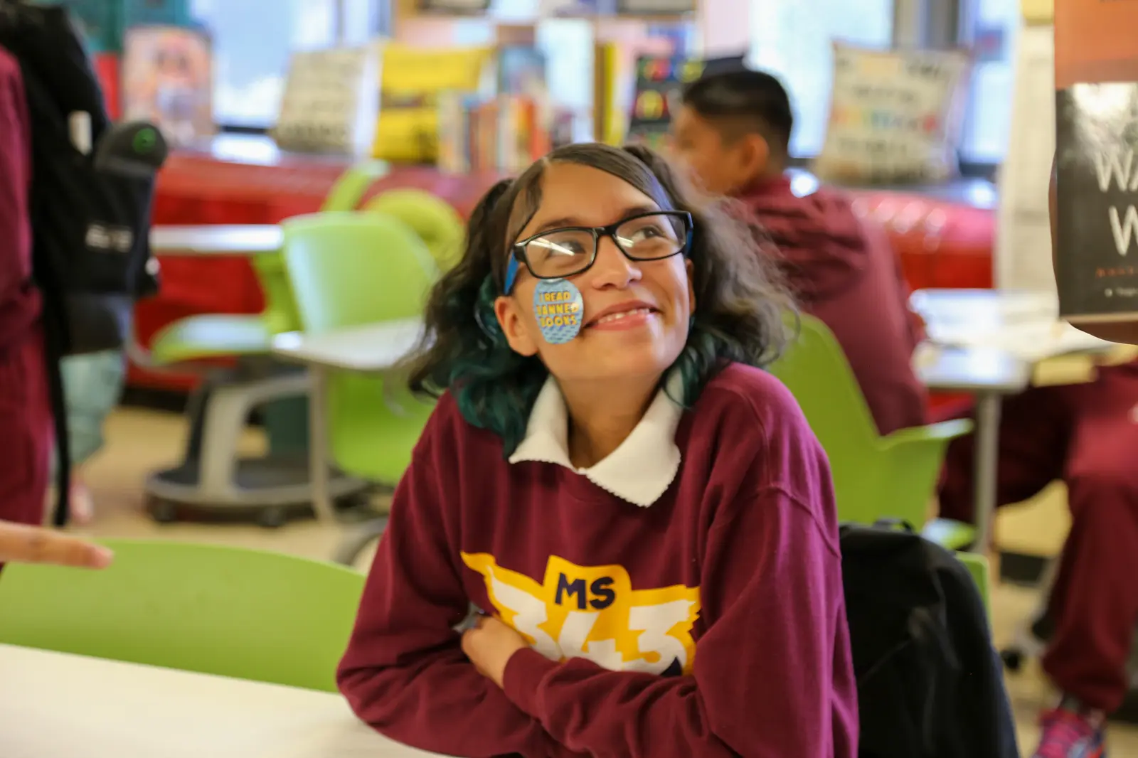 Smiling student wearing MS 343 sweatshirt and glasses in classroom