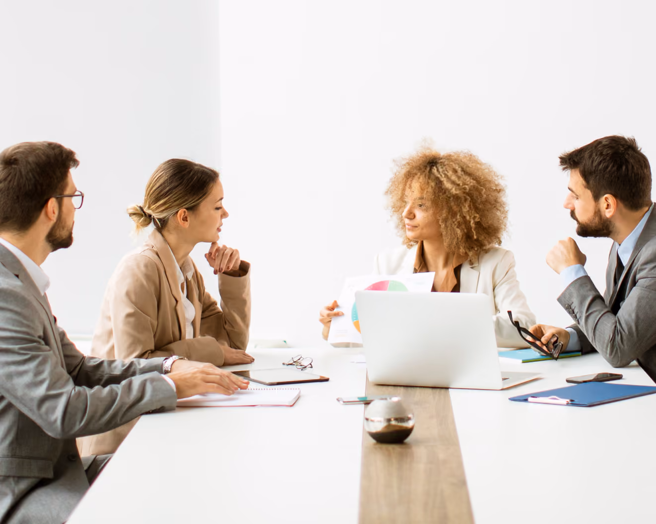 Four people in a business meeting discussing documents around a conference table