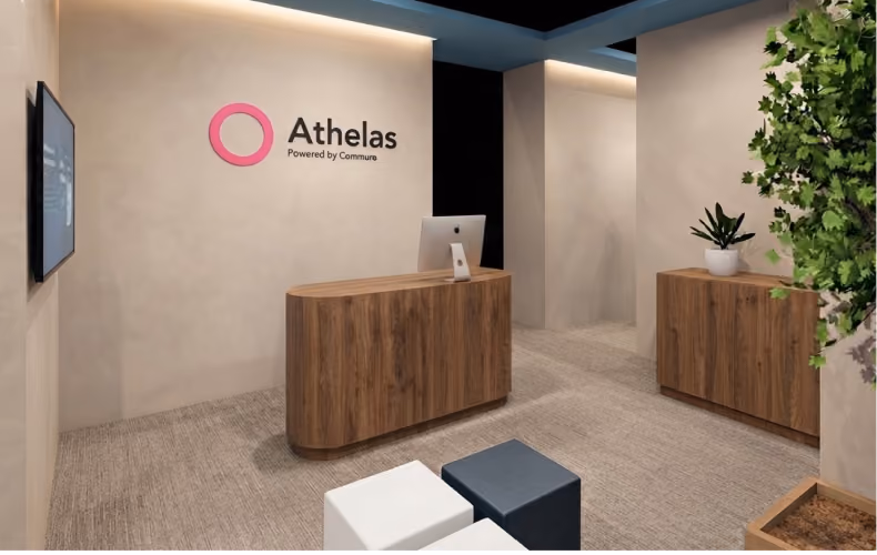 Athelas exhibition booth at PPS 2026, featuring branded walls, wooden reception counters, modern seating, and greenery.
