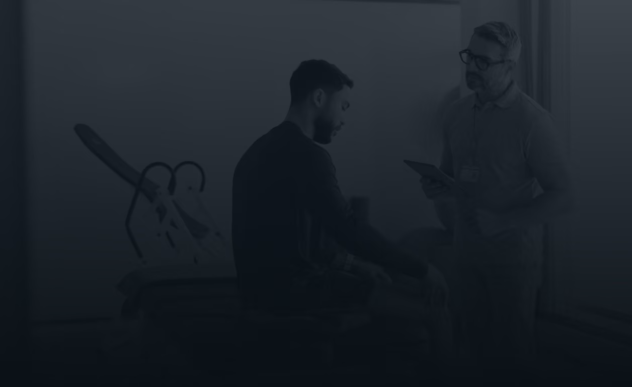 A physical therapist consulting with a seated patient in a treatment room.