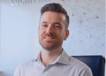 Smiling man in a white shirt speaking in an office.