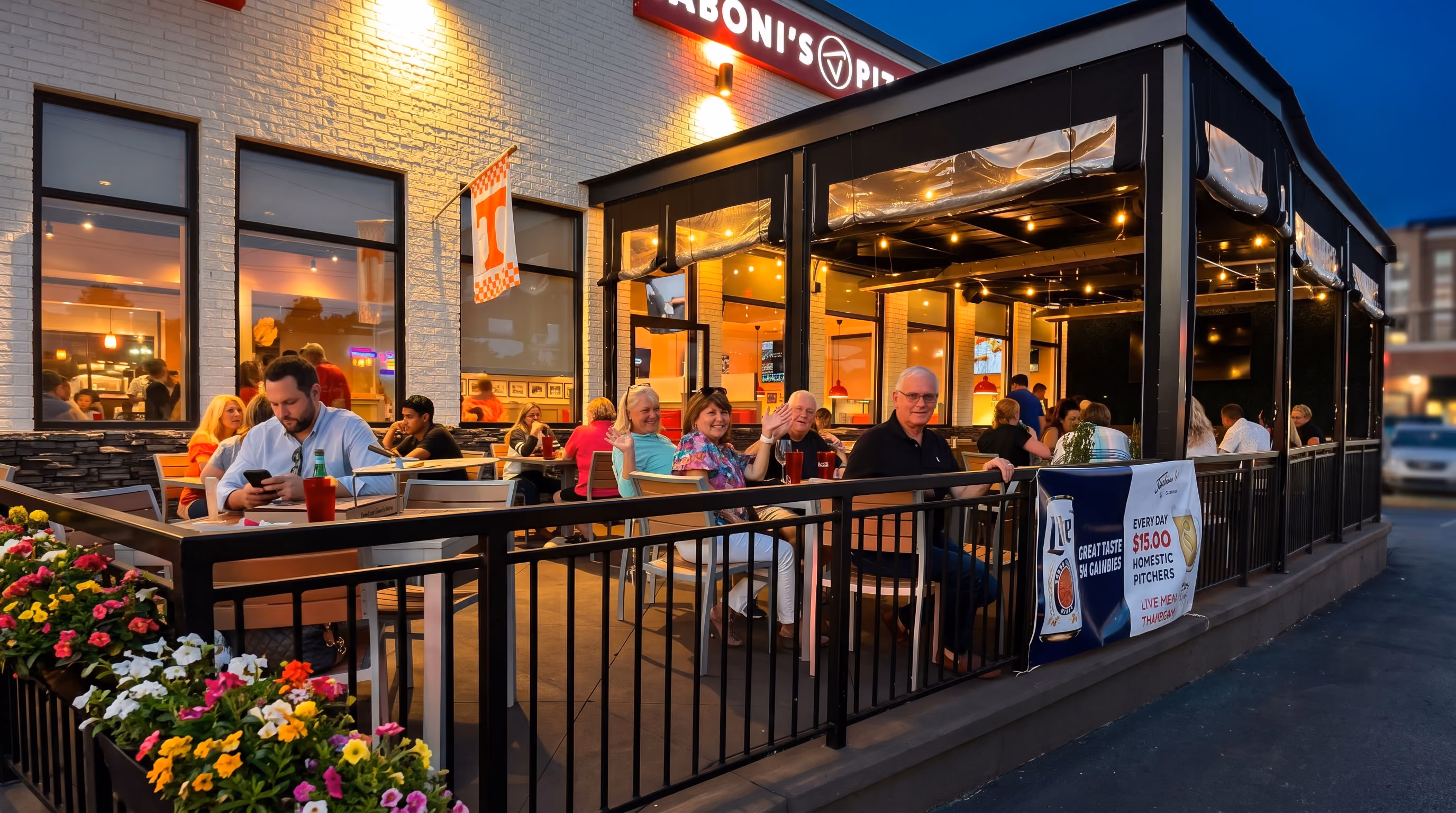 People dining and socializing at Jaboni's Pizzeria outdoor patio in the evening.