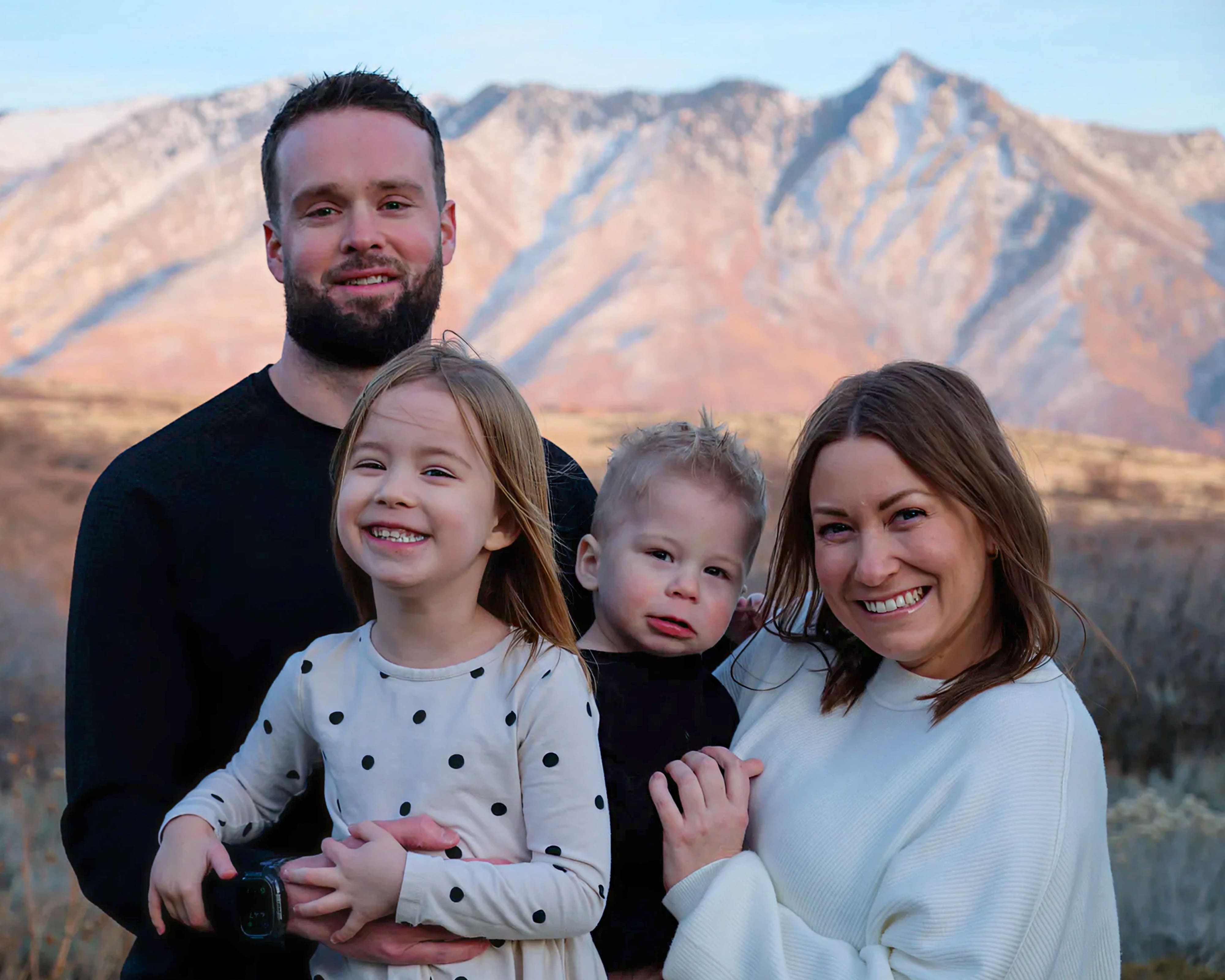 Bre with her husband, daughter and young son in front of a snowy mountain range