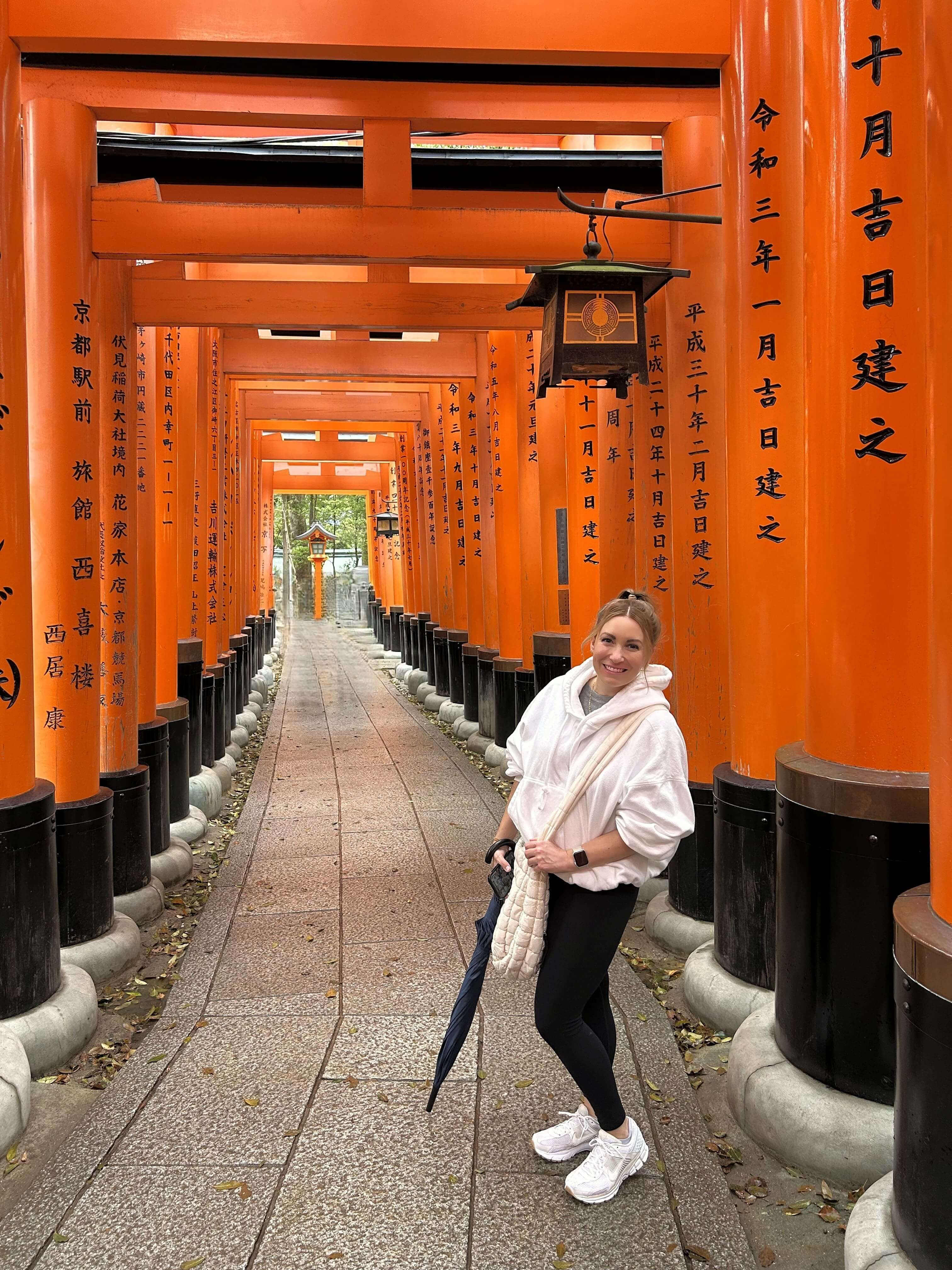 Bre walking through the orange torii gate tunnel at Fushimi Inari Shrine in Kyoto