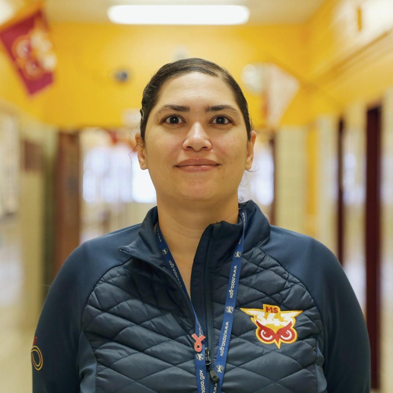 Ms. Wells staff member standing in school hallway wearing lanyard