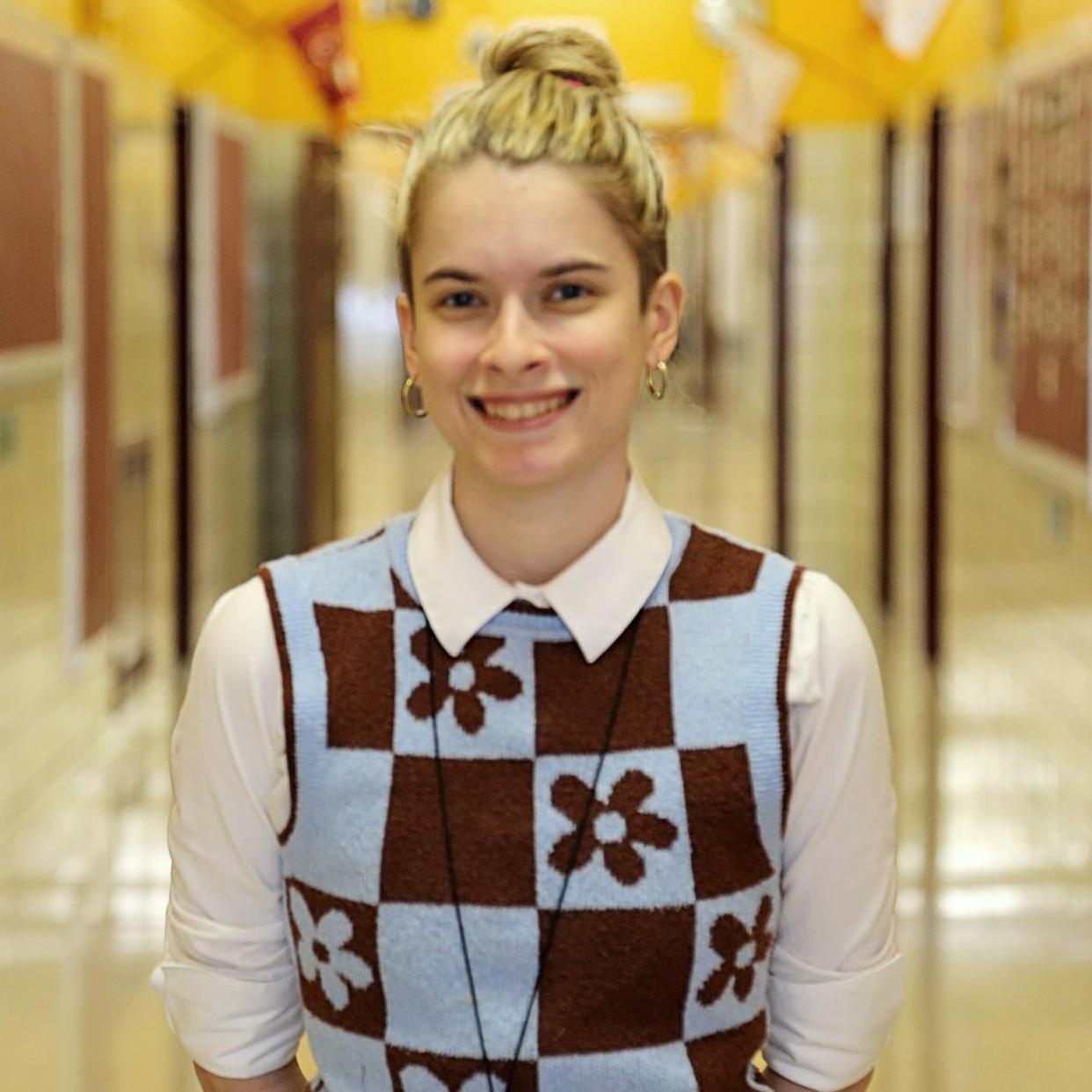 Mx. Demacopoulos smiling in a school hallway