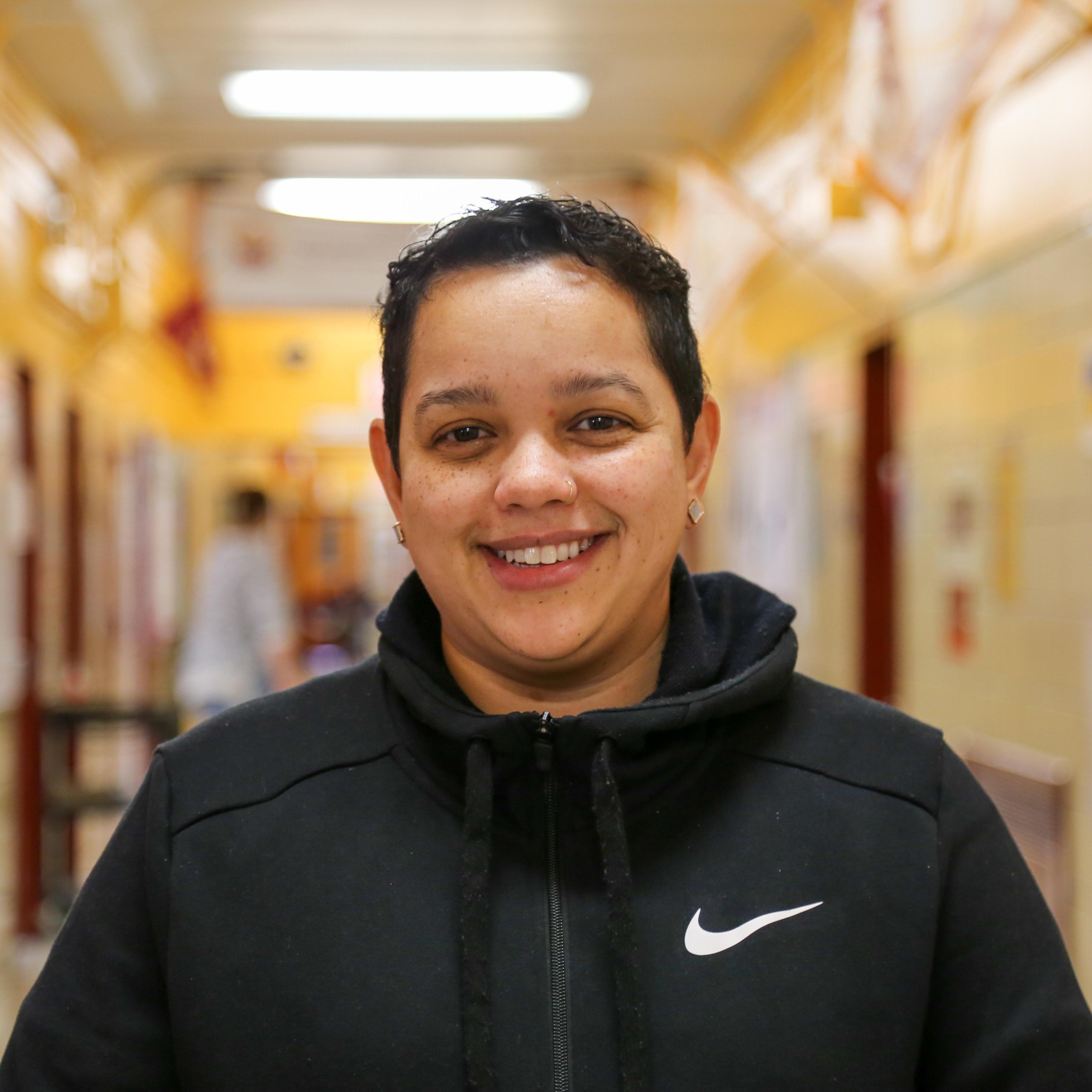 Ms T Pagan smiling in a school hallway