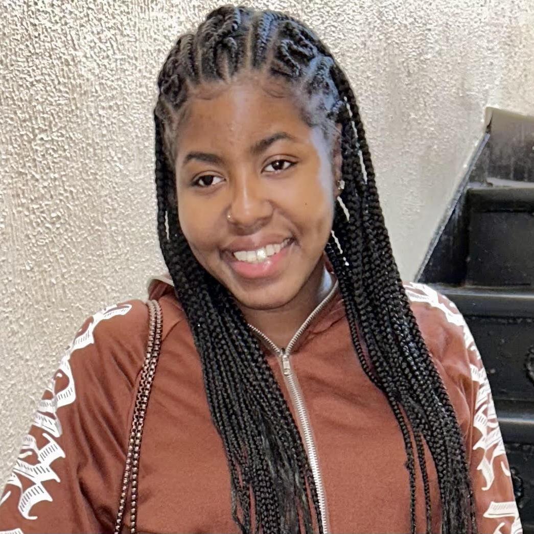 Ms. Wood smiling in a brown zip-up jacket