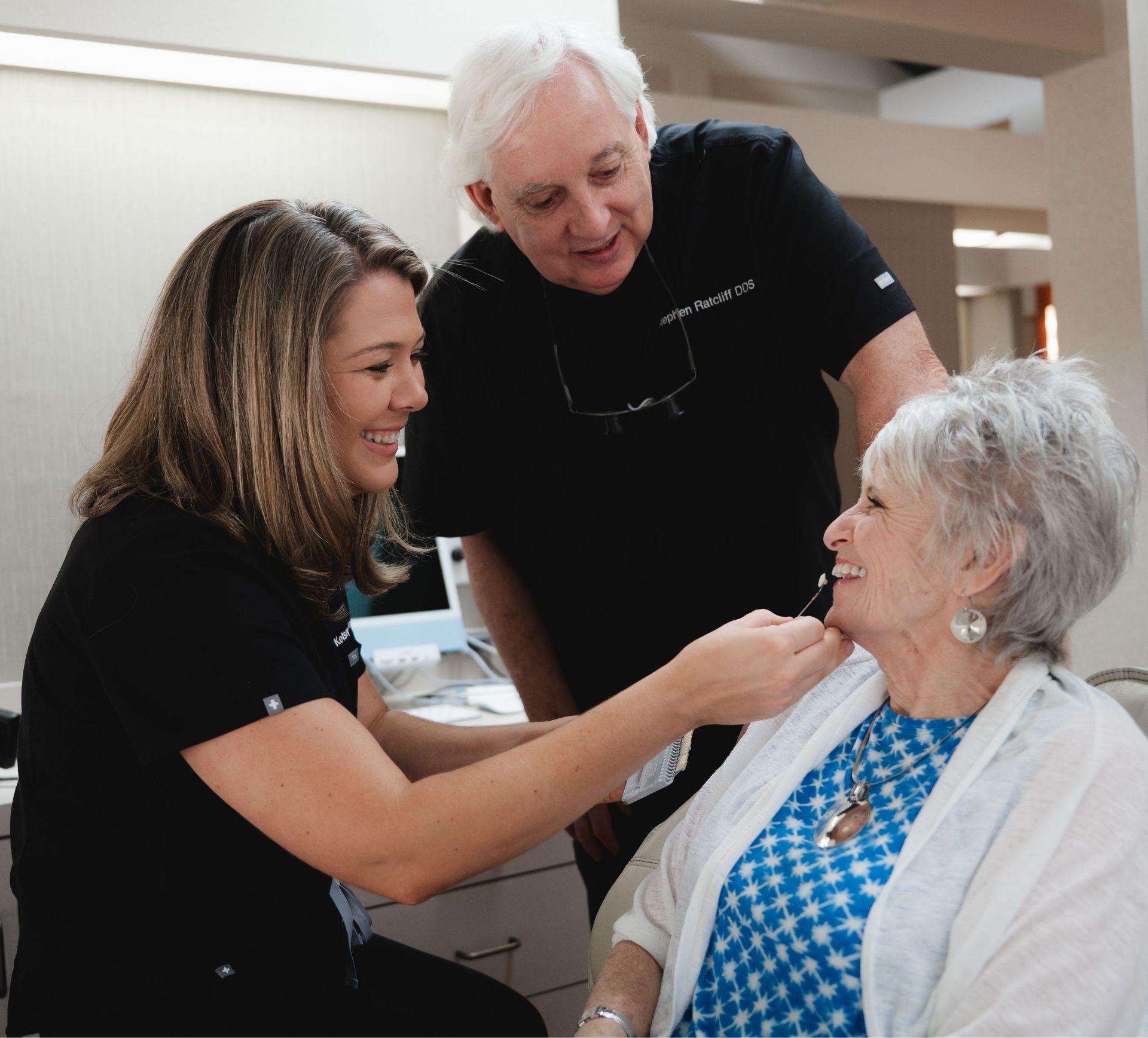 Dr. Ratcliff and a team member examining a smiling senior patient.