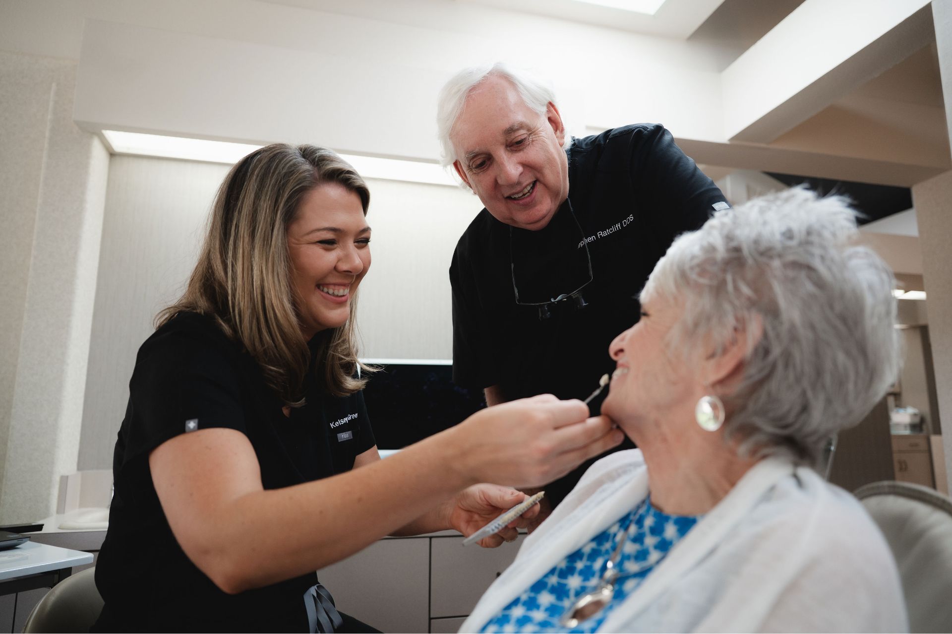Dr. Ratcliff and a team member examining a smiling senior patient.