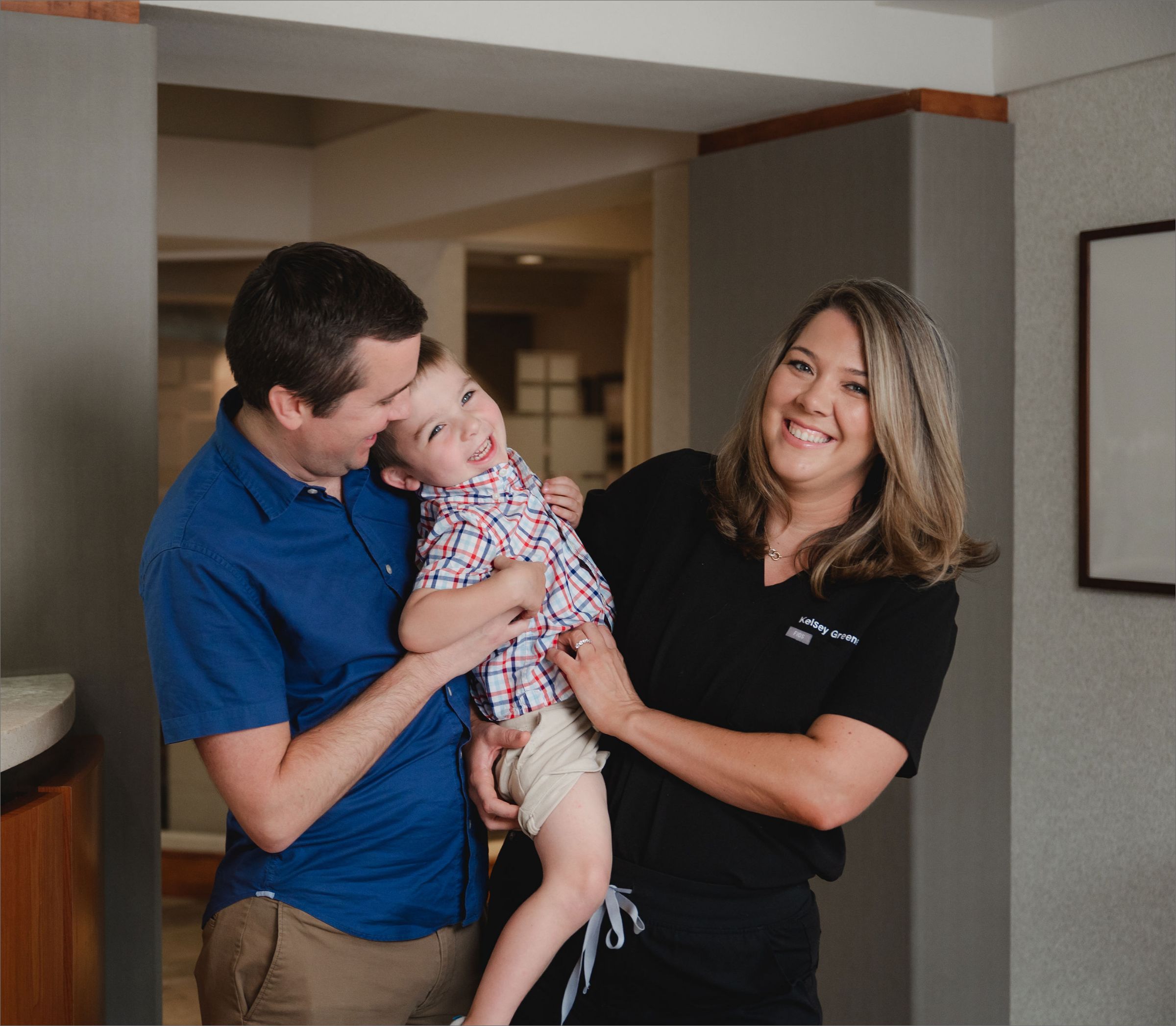 Father holding his smiling toddler next to a Greene & Ratcliff team member.