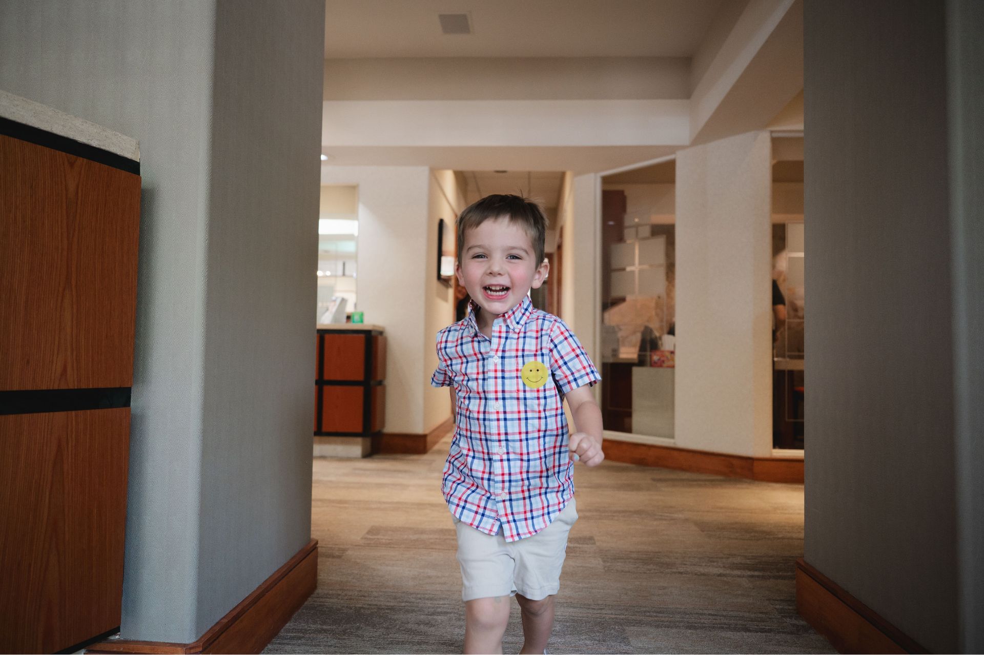 Young boy running and smiling down a hallway at the Greene & Ratcliff office.