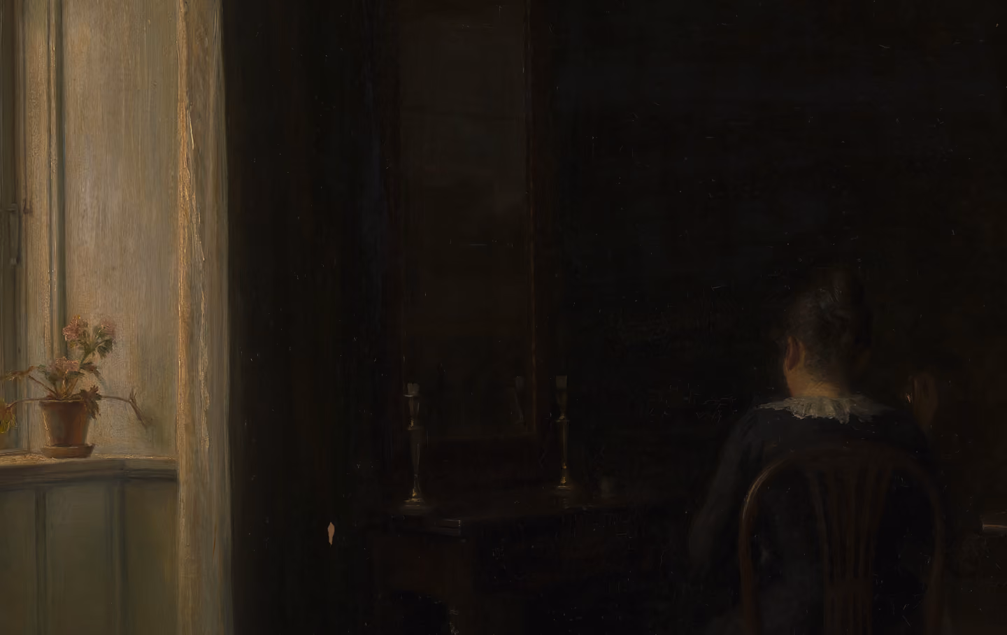 Dimly lit room with a woman sitting on a wooden chair facing a dark dressing table with a mirror, a potted plant on the window sill to the left.