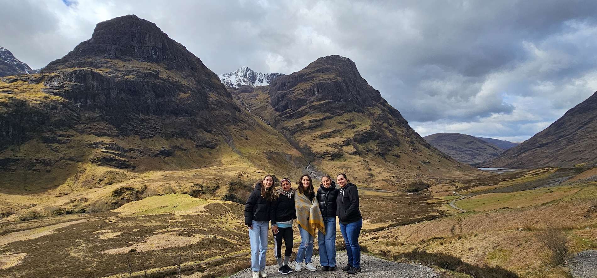 Tour guests posing at the Three Sisters of Glencoe on a day tour from Edinburgh