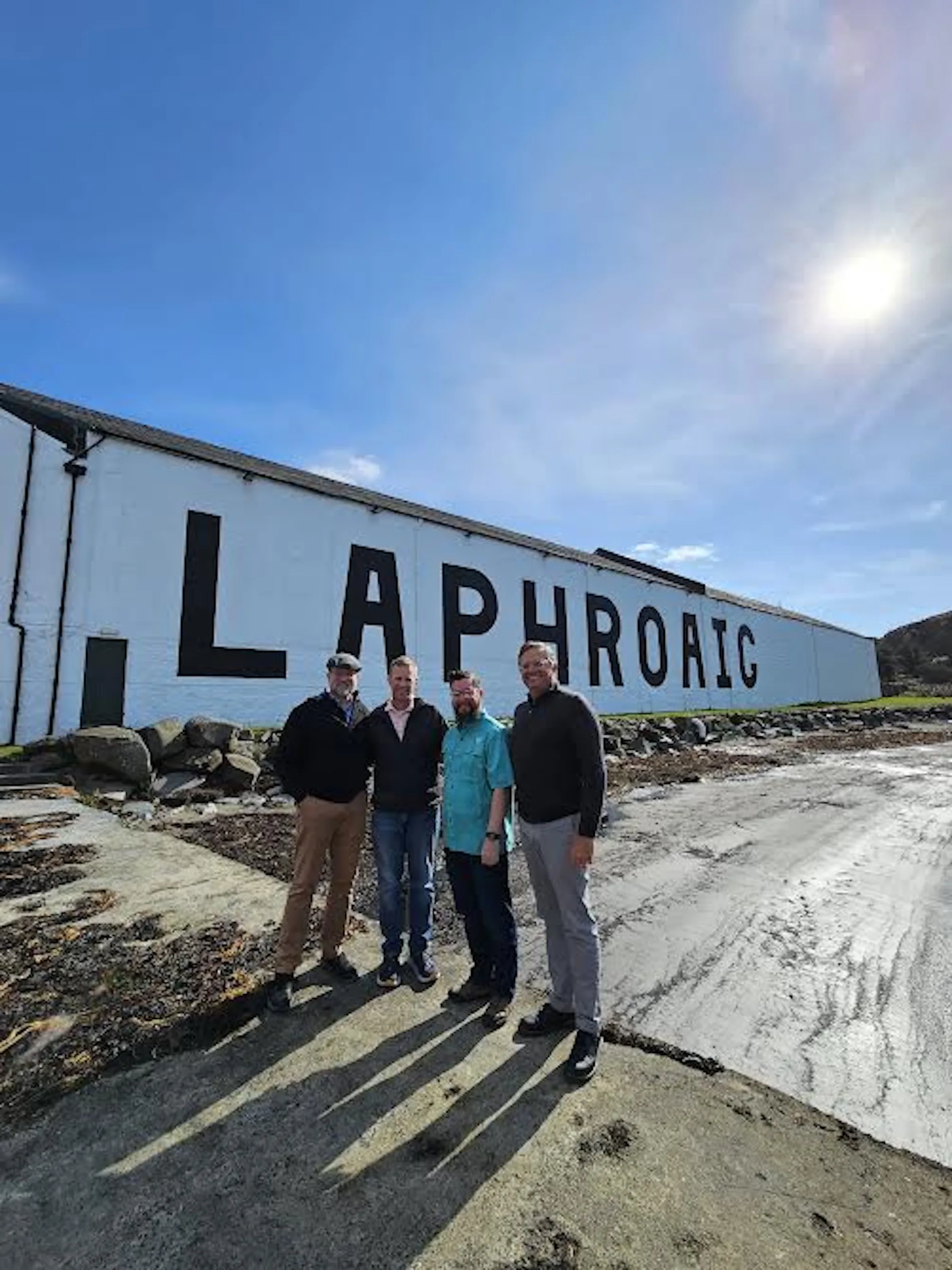 Four tourists posing at Laphroaig whisky distillery in Scotland