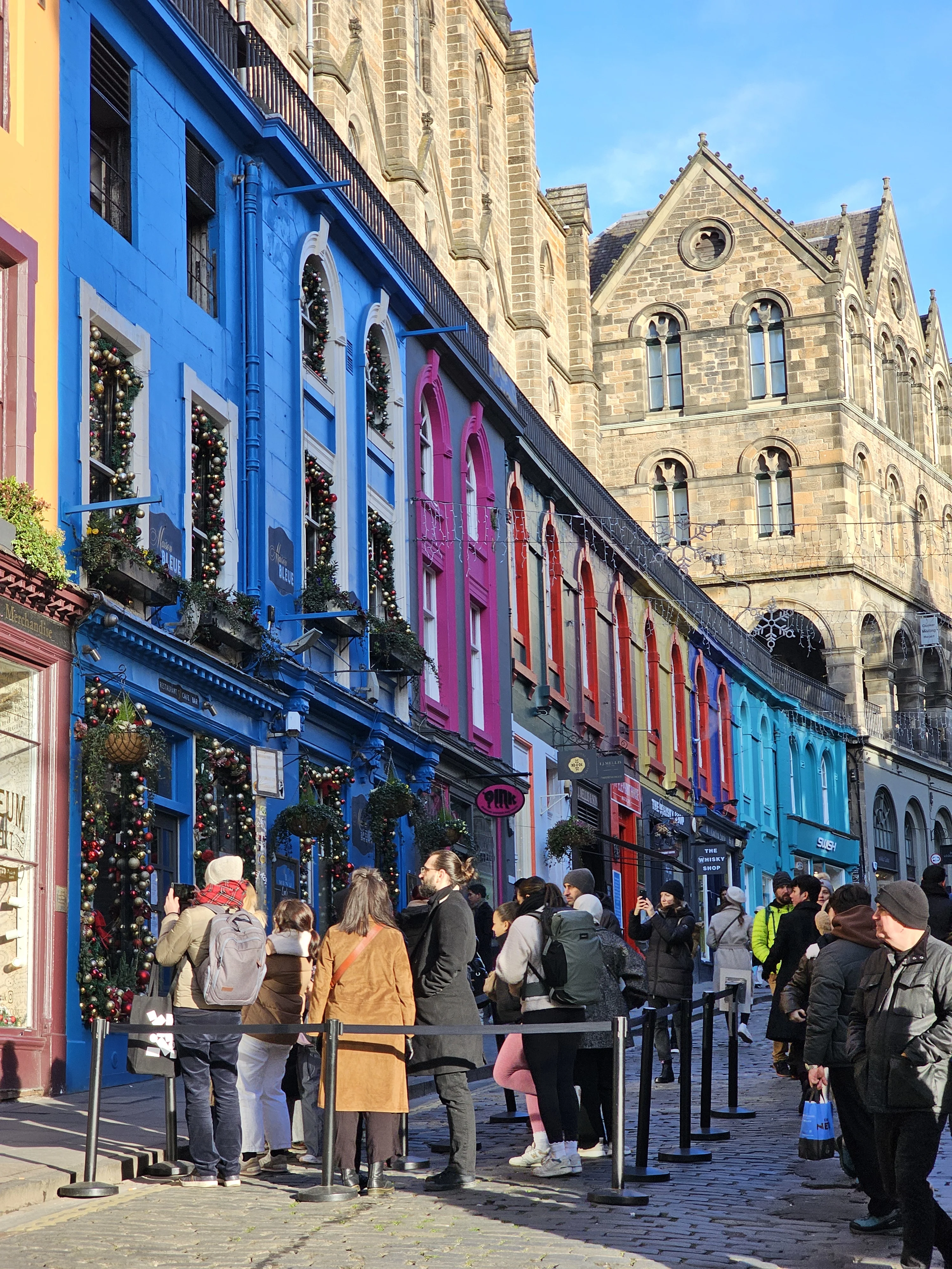 Colorful shopfronts and tourists in Edinburgh's historic Old Town street