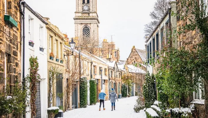 Historic Scottish stone street with clock tower and ivy-covered buildings
