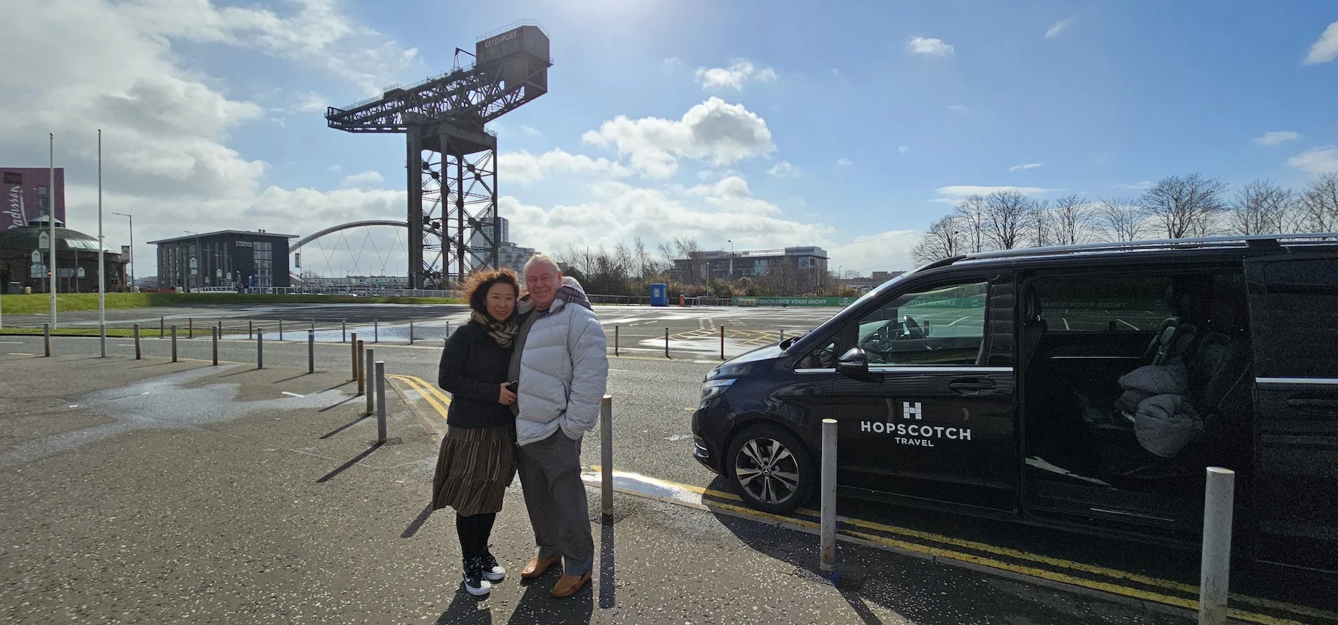 Couple posing beside Hopscotch Travel van at Glasgow Riverside industrial heritage site