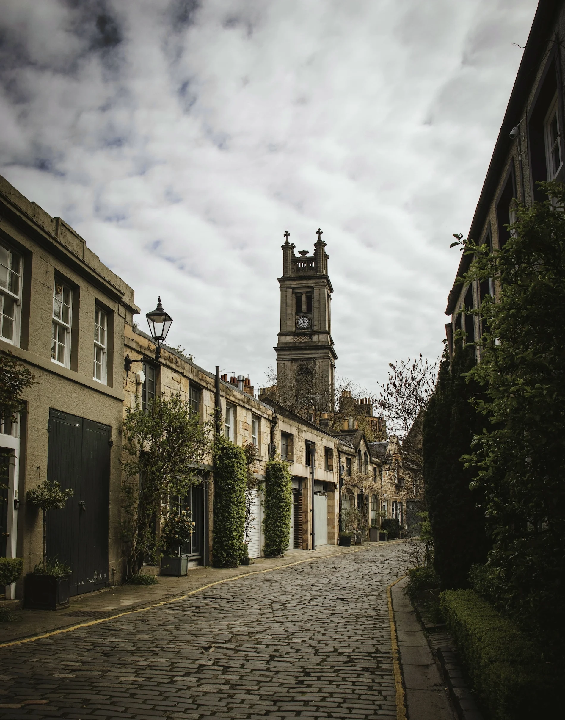 Historic Scottish street with stone buildings and church tower in distance