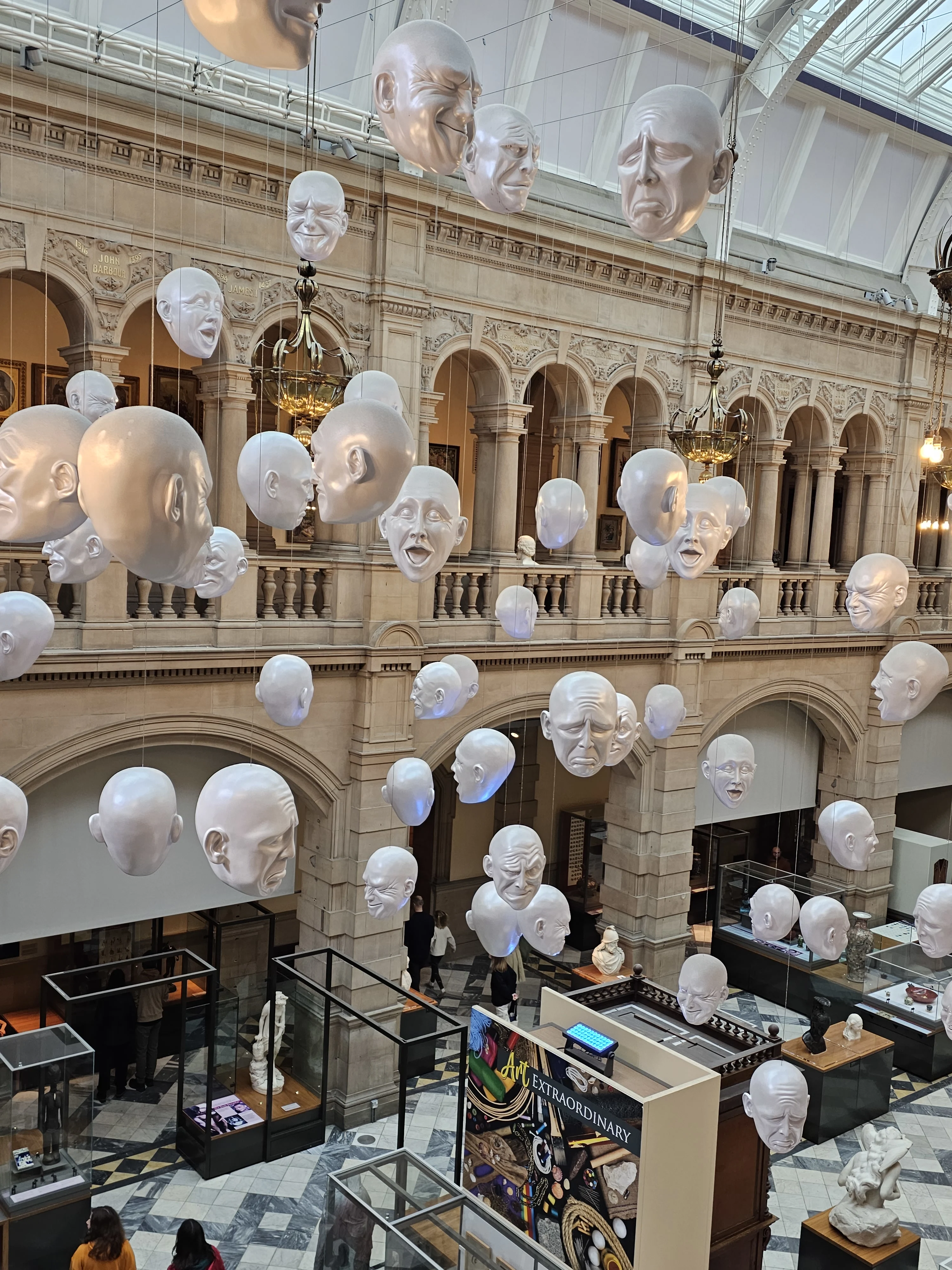 White plaster face sculptures suspended in ornate historic gallery interior