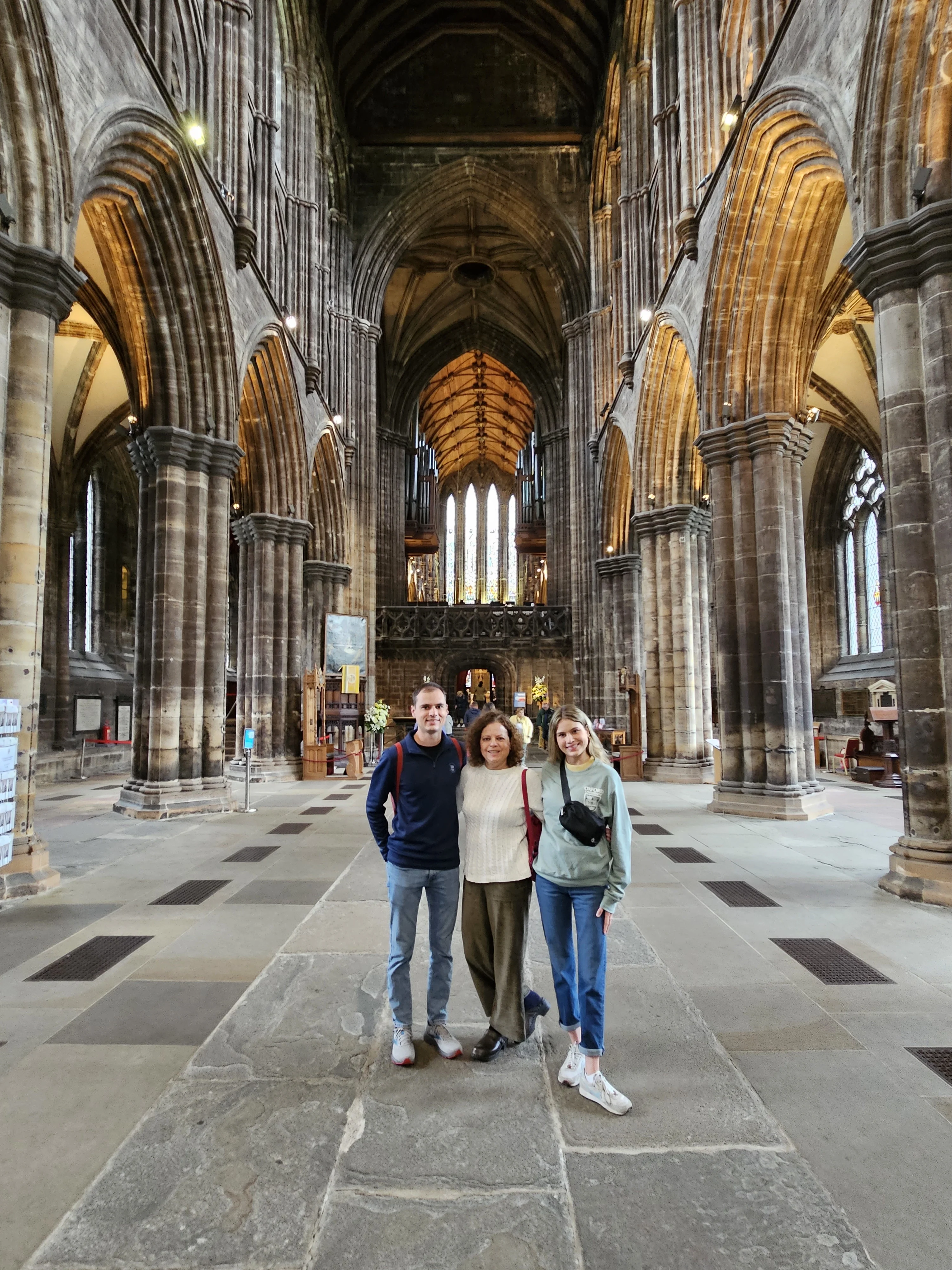 Three visitors posing inside Edinburgh's historic gothic cathedral nave