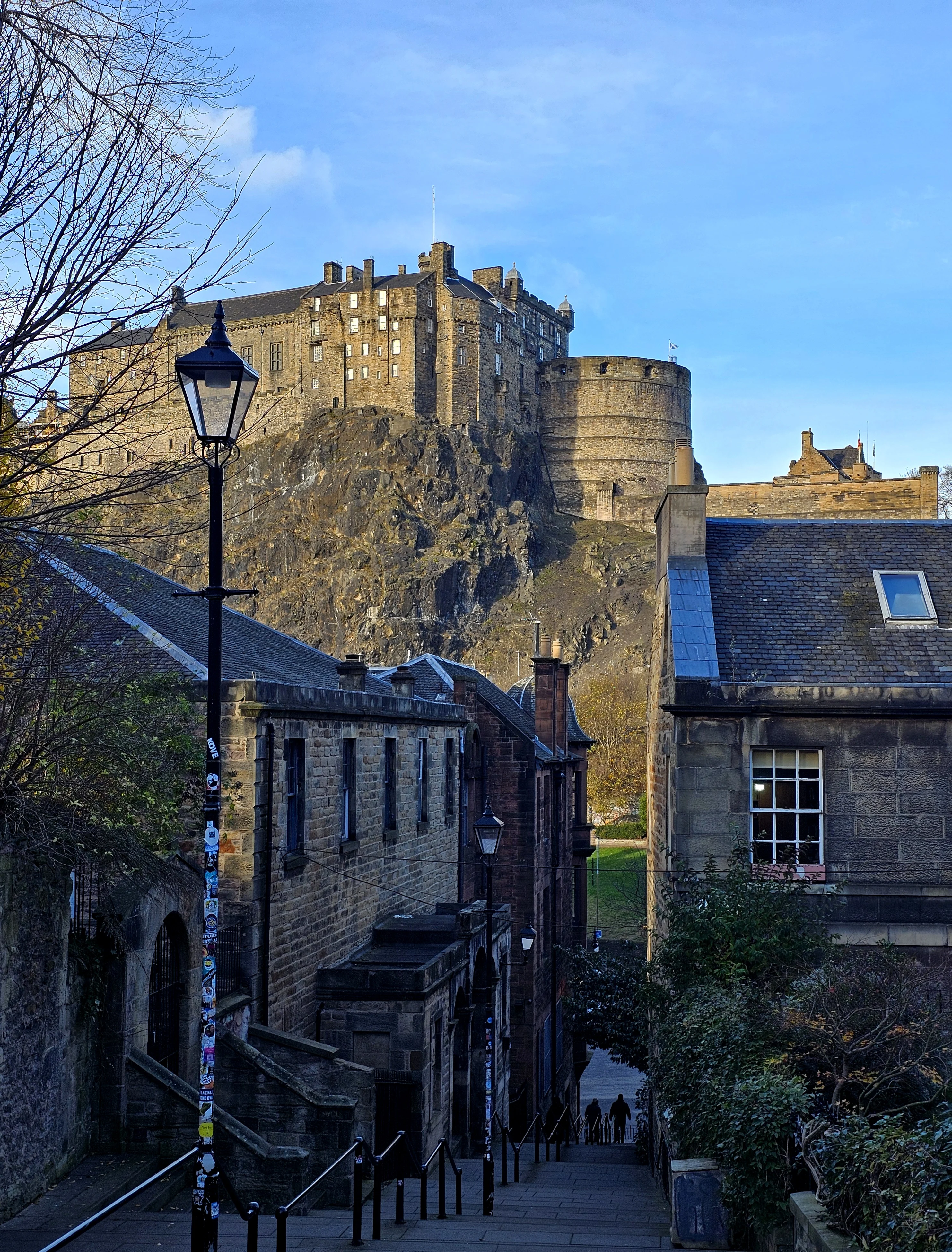 Edinburgh Castle towering above historic stone buildings and cobbled street