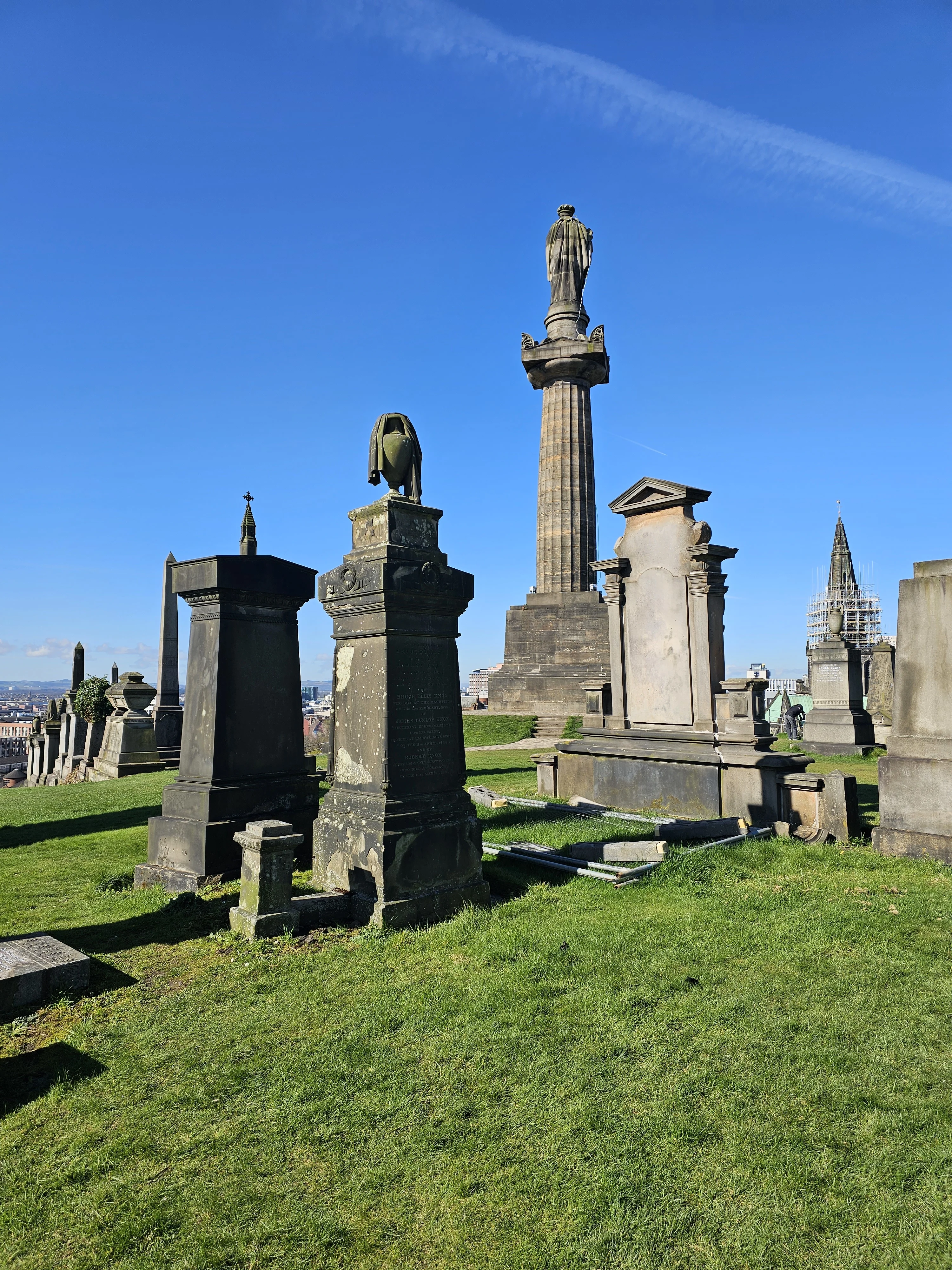 Historic gravestones and monuments in Edinburgh cemetery with city skyline
