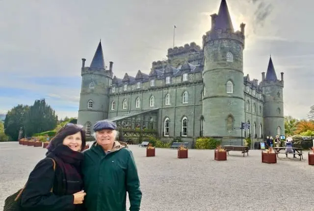 Couple posing in front of Scottish castle with blue towers