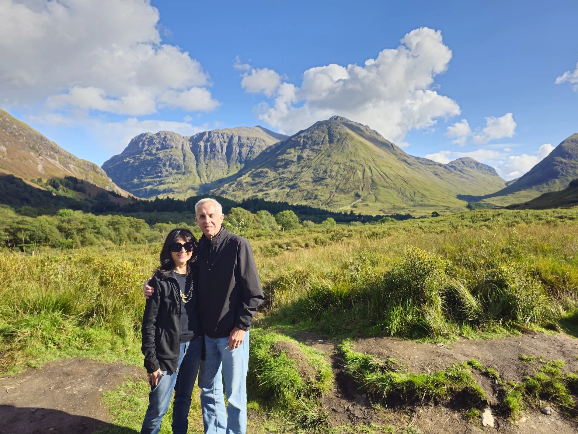 Couple posing in Scottish Highland valley with dramatic mountains behind