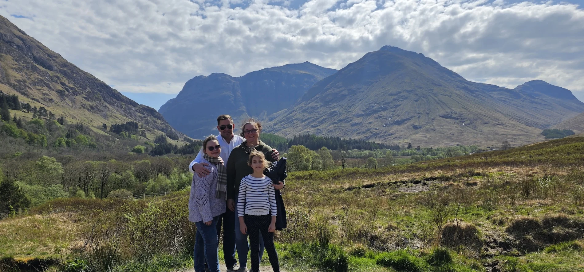 Family posing in Scottish Highland valley with mountains in background