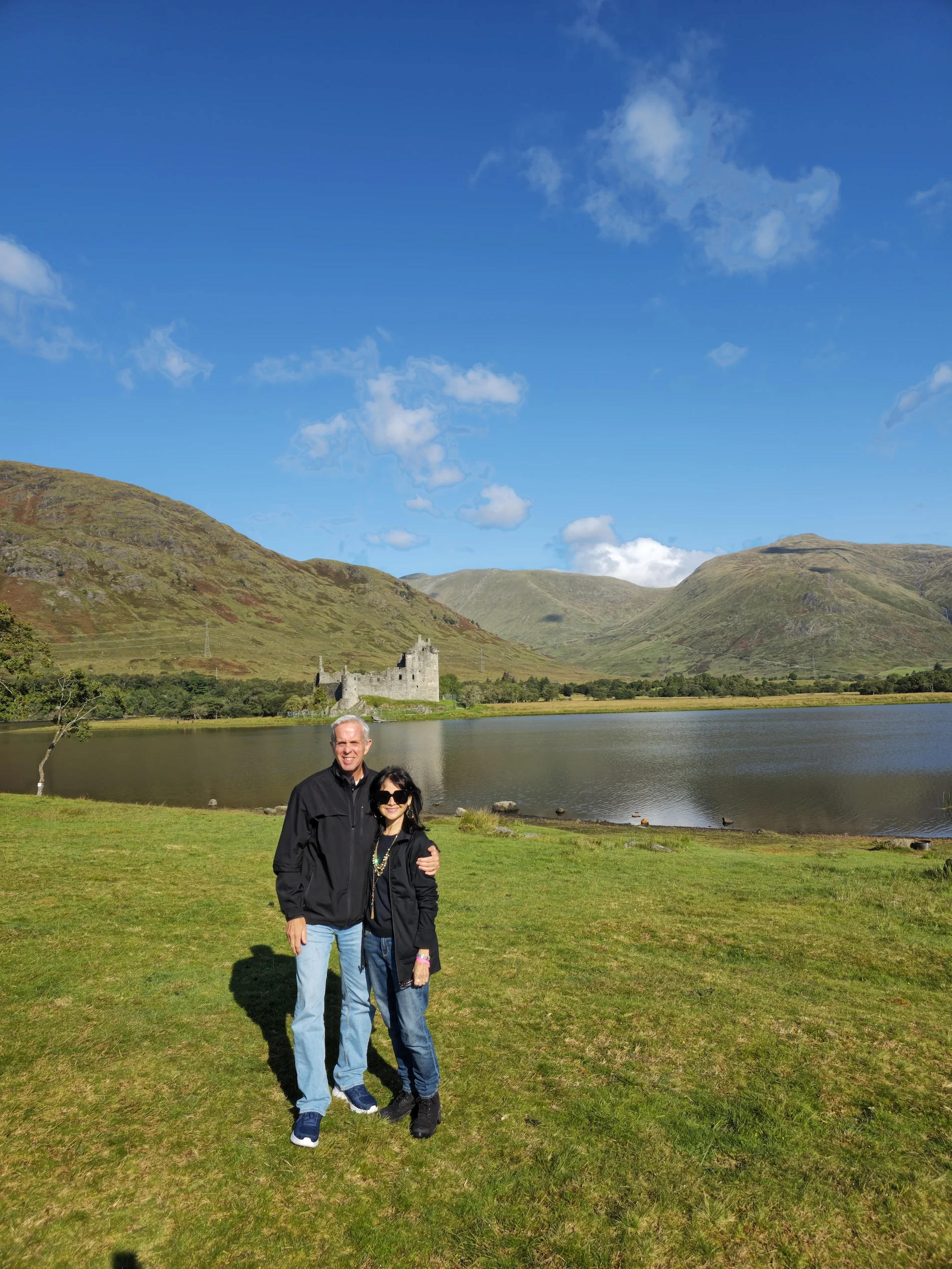 Couple posing at Kilchurn Castle with Scottish loch and mountains