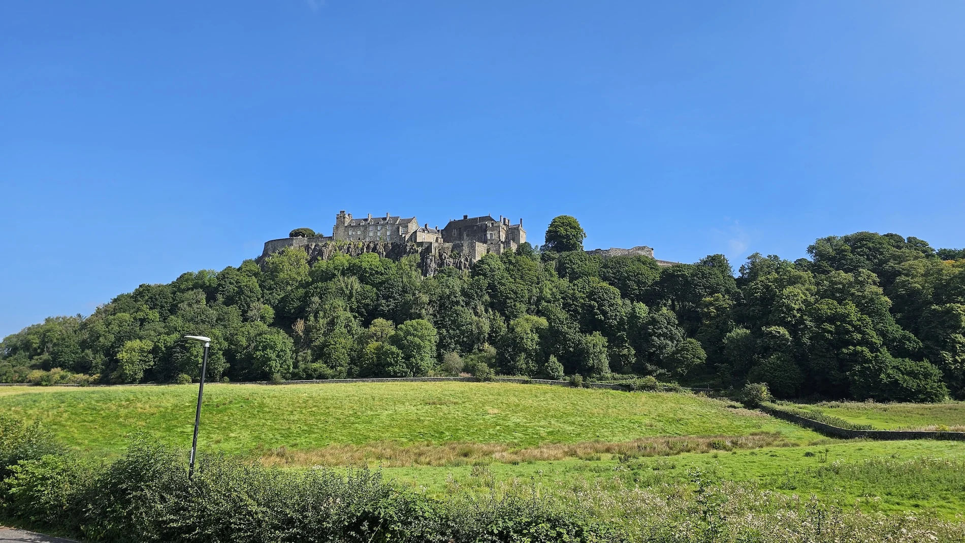 Historic Scottish castle perched on forested hilltop overlooking green valley